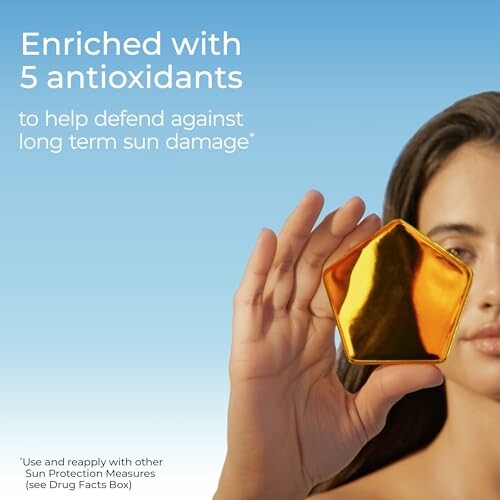 Person holding a golden sunscreen container with text about antioxidants for sun protection.